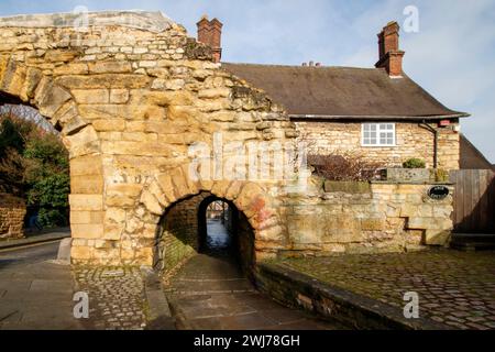 Il Newport Arch e la strada che porta a Bailgate, l'area superiore di Lincoln. Newport Arch è una porta romana del III secolo nella città di Lincoln, nel Lincolnshire. Si tratta di un monumento e di un edificio classificato di grado i ed è considerato l'arco più antico del Regno Unito ancora utilizzato dal traffico. Foto Stock