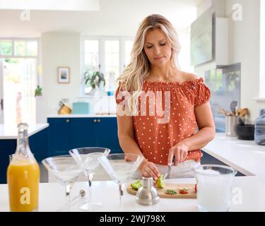 Donna matura in Kitchen at Home che prepara ingredienti per cocktail fatti in casa Foto Stock