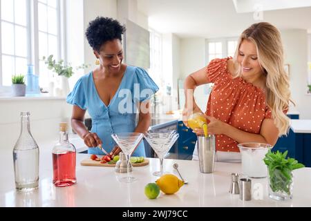 Due amiche mature a casa che si divertono a mescolare cocktail insieme Foto Stock
