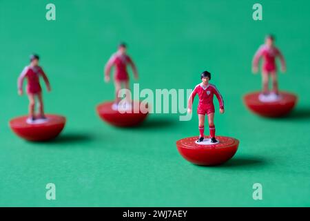 Un gruppo di figure in miniatura di Subbuteo dipinte nei colori della squadra di casa del Liverpool FC con camicia rossa, pantaloncini corti rossi e calze rosse. Foto Stock