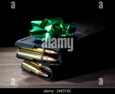 Prua verde sopra due caricatori AR-15 ad alta capacità caricati su un tavolo come regalo per il proprietario di una pistola. Foto Stock