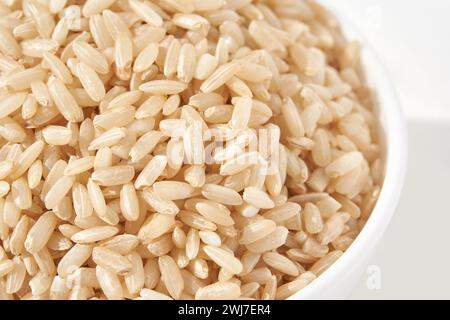 Una ciotola di riso integrale crudo, isolata su sfondo bianco. Il piatto sano e salato include cereali integrali come gelsomino e basmati, che mostrano una cucina asiatica dietetica. Foto Stock