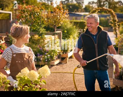 Uomo maturo e donna che lavorano all'aperto nelle piante da irrigazione del Garden Centre Foto Stock