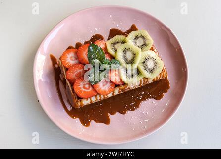 Waffle fantastici con fragole, kiwi e sciroppo di caramello Foto Stock
