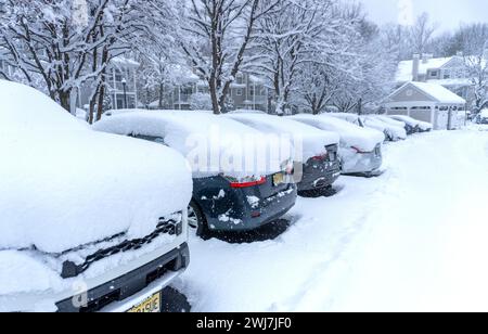 Auto coperte di neve nel parcheggio di un complesso di appartamenti Foto Stock