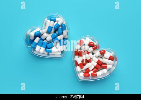 Pillole colorate a forma di cuore primo piano su sfondo blu, capsule mediche, vista dall'alto. San Valentino. Integratori alimentari. vit. Farmaceutico assortito Foto Stock