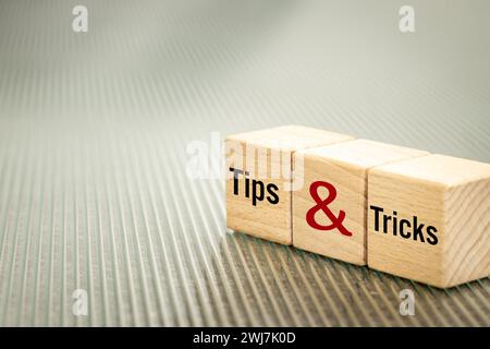 Simbolo di suggerimenti e trucchi, parole d'affari scritte su blocchi di legno, concetto di suggerimenti e trucchi. Copia spazio. Splendido sfondo in vetro scanalato, spazio di copia Foto Stock