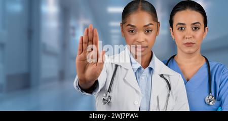 Due operatori sanitari professionisti, una in un camice bianco da laboratorio che si fermano con gesti Foto Stock
