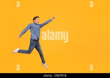 Guarda questo. Teen boy che punta da parte mentre salta in aria Foto Stock