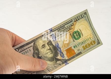 Autenticazione della banconota da 100 dollari per l'autorizzazione. Filigrane su una banconota da 100 dollari. Banconota in mano su sfondo bianco con filigrana. Frankl Foto Stock