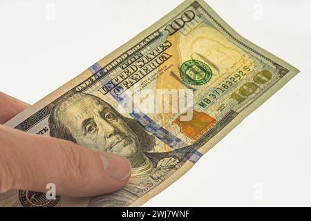 Autenticazione della banconota da 100 dollari per l'autorizzazione. Filigrane su una banconota da 100 dollari. Banconota in mano su sfondo bianco con filigrana. Frankl Foto Stock