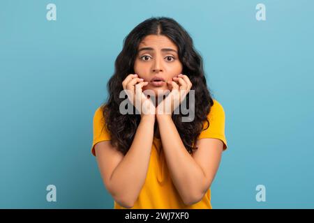 Sconvolta la giovane donna indiana che si tocca la faccia Foto Stock