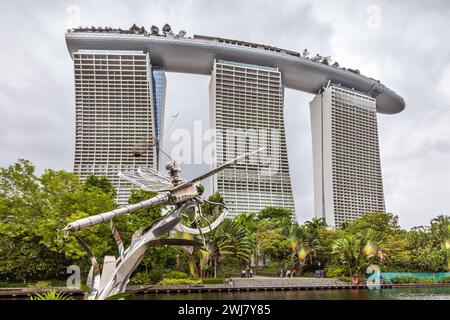 Scultura in metallo della libellula presso i Gardens by the Bay con sullo sfondo l'iconico Marina Bay Sands Hotel Foto Stock