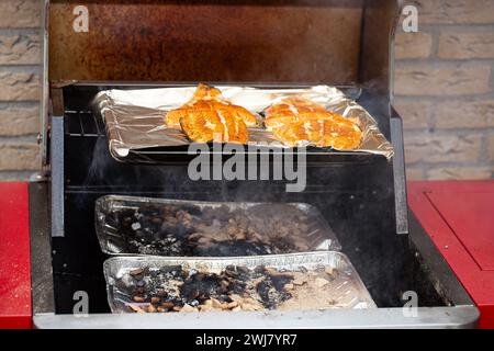 Primo piano di una cucina all'aperto con un lembo aperto che mostra bistecche fresche di salmone selvatico da affumicare con legno di mele e legno di quercia Foto Stock