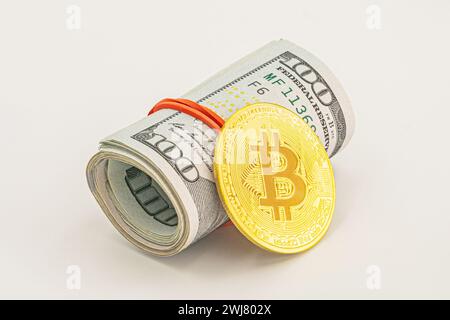bitcoin BTC moneta e rotolo di banconote da un dollaro banconote sfondo bianco. Banconote in dollari americani in rotoli con moneta Bitcoin d'argento. Foto Stock