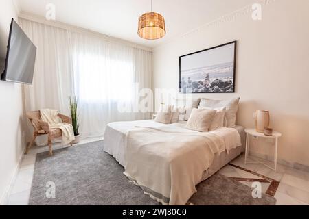un'accogliente camera da letto arredata completa di tv e sedia nella casa vacanze mediterranea Foto Stock