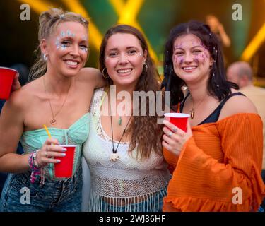 Ritratto di tre amiche che indossano Glitter Having Fun al Summer Music Festival con drink Foto Stock