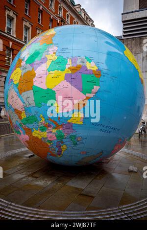 LSE London - Grande globo invertito al campus della London School of Economics nel centro di Londra. Il mondo capovolto scultura di Mark Wallinger Foto Stock