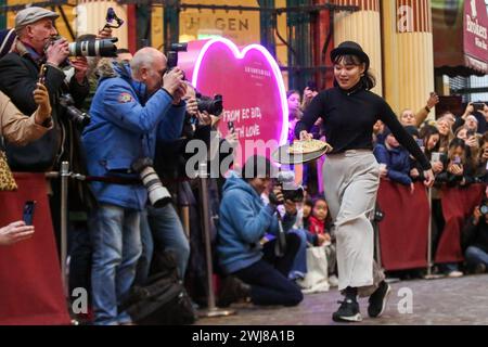 Londra, Regno Unito. 13 febbraio 2024. Un partecipante prende parte alla gara annuale di Shrove pancake Day al mercato di Leadenhall nel centro di Londra. Ospitato dal pub del XVIII secolo Markets C, l'Lamb Tavern C, l'evento tradizionale annuale, le squadre competono per la gloria durante una staffetta di 20 metri sui mercati coperti vittoriani antichi ciottoli. Credito: SOPA Images Limited/Alamy Live News Foto Stock