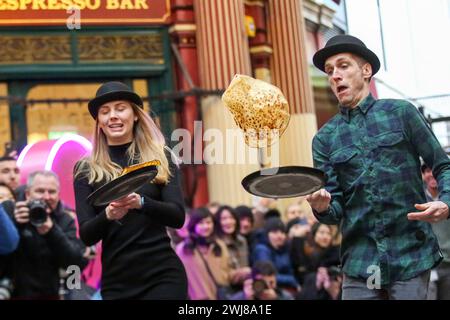 Londra, Regno Unito. 13 febbraio 2024. I partecipanti prendono parte alla gara annuale Shrove Pancake Day al Leadenhall Market nel centro di Londra. Ospitato dal pub del XVIII secolo Markets C, l'Lamb Tavern C, l'evento tradizionale annuale, le squadre competono per la gloria durante una staffetta di 20 metri sui mercati coperti vittoriani antichi ciottoli. Credito: SOPA Images Limited/Alamy Live News Foto Stock