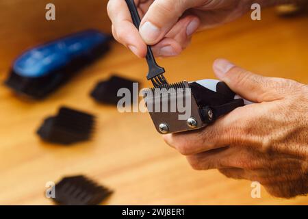 Parrucchiere che pulisce la macchina regolacapelli con una piccola spazzola. Manutenzione dell'attrezzatura. Foto Stock