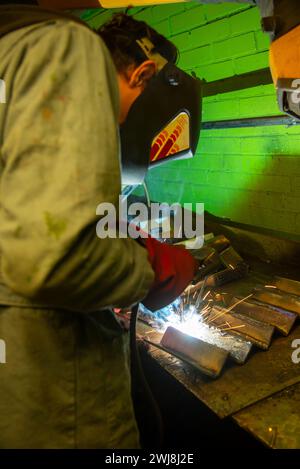 giovane uomo che salda parti metalliche Foto Stock