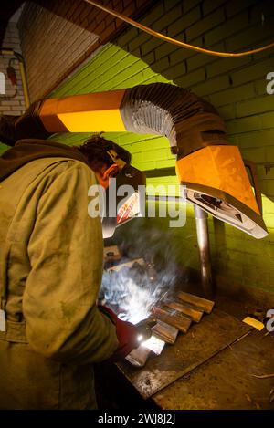 giovane uomo che salda parti metalliche Foto Stock