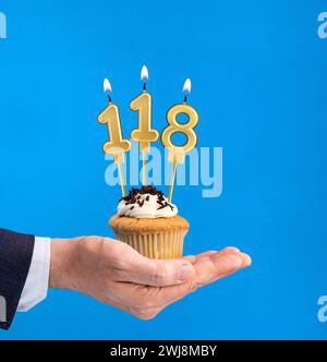 Cupcake per il compleanno a mano - candela numero 118 su sfondo blu Foto Stock