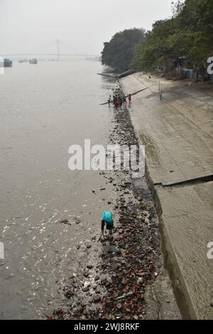 Sullo sfondo degli iconici Ghati di Kolkata, una comunità di fanghi ha fatto di una scoperta notevole parte della loro routine quotidiana. Armati di metal detector e setacci, questi appassionati setacciano il letto del fiume esposto durante la bassa marea, scoprendo monete, gioielli e manufatti risalenti a secoli fa. I loro reperti non solo servono come testimonianza del vibrante passato di Kolkata, ma contribuiscono anche alla conservazione del suo patrimonio culturale. Nonostante si trovino di fronte a sfide come l'inquinamento e il calo dei livelli dell'acqua, queste larve di fango persistono nella loro ricerca di tesori nascosti. I loro sforzi hanno g Foto Stock