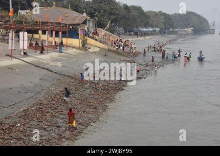 Kolkata, Bengala Occidentale, India. 13 febbraio 2024. Sullo sfondo degli iconici Ghati di Kolkata, una comunità di fanghi ha fatto di una scoperta notevole parte della loro routine quotidiana. Armati di metal detector e setacci, questi appassionati setacciano il letto del fiume esposto durante la bassa marea, scoprendo monete, gioielli e manufatti risalenti a secoli fa. I loro reperti non solo servono come testimonianza del vibrante passato di Kolkata, ma contribuiscono anche alla conservazione del suo patrimonio culturale. Nonostante si trovino di fronte a sfide come l'inquinamento e il calo dei livelli dell'acqua, queste larve di fango continuano a persistere nel loro Foto Stock