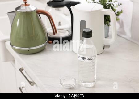 Pulizia del bollitore elettrico. Bottiglia di aceto e bicarbonato sul ripiano della cucina Foto Stock