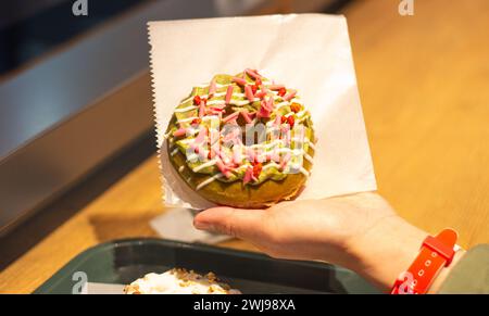 La mano della ragazza tiene in mano un gustoso tè verde e una ciambella alla crema di fragole (ciambella) a Osaka, Giappone Foto Stock