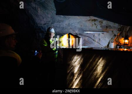 Un minatore spiega a un visitatore le proprietà delle rocce durante una visita alla miniera di Bergtatt. Bergtatt è una straordinaria miniera di marmo situata nella contea di Møre og Romsdal, vicino alla città di Eide, nella regione occidentale della Norvegia. Offre visite guidate attraverso grotte sotterranee. L'esperienza include un giro in barca su un lago sotterraneo illuminato e una sala concerti scolpita nel marmo. Il sito è noto per la sua bellezza naturale e l'acustica unica, rendendolo una destinazione memorabile per i visitatori. (Foto di Jorge Castellanos/SOPA Images/Sipa USA) Foto Stock