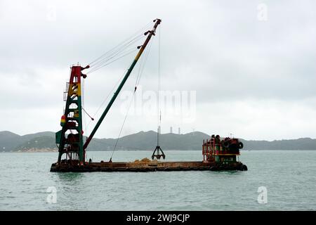 Una chiatta di sabbia vicino all'Isola di AP lei Chau che porta sabbia e materiali da costruzione per la costruzione della stazione MTR di South Horizons a Hong Kong. Foto Stock