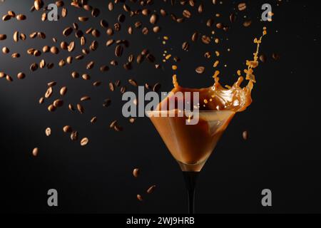 Espresso Martini con schizzi e chicchi di caffè cadenti su sfondo nero. Copia spazio. Foto Stock