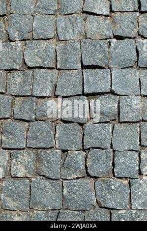 Fondo pavimentato in granito acciottolato, regolari forme di sentiero in pietra acciottolata, sfondo astratto di vecchi marciapiedi in ciottoli. Strade nel centro storico Foto Stock