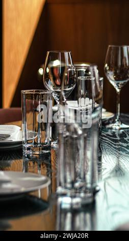 Tavolo in legno con piatti, bicchieri, argenteria e bicchieri da vino Foto Stock