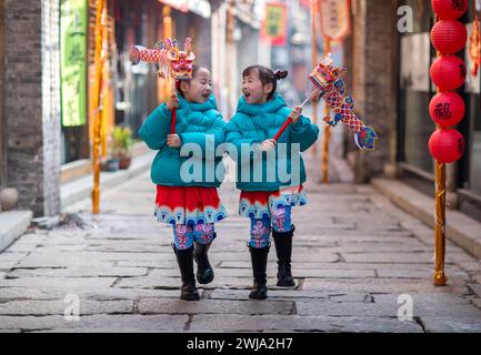 Pechino, la provincia cinese di Jiangsu. 11 febbraio 2024. Una coppia di gemelli gioca in un sito culturale e turistico nella città di Xinghua, nella provincia di Jiangsu, nella Cina orientale, l'11 febbraio 2024. Molte persone scelgono di indossare costumi cinesi tradizionali per celebrare il capodanno cinese. Crediti: Zhou Shegen/Xinhua/Alamy Live News Foto Stock