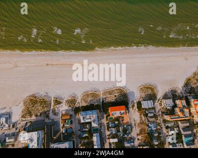 Uno scatto aereo cattura il tranquillo fronte spiaggia di Miami, Florida, circondato da verde verdeggiante e da una costa tranquilla mentre la sera si avvicina. Foto Stock