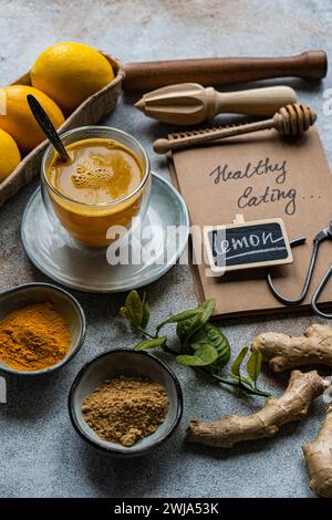 Una cucina rustica caratterizzata da limoni freschi, un bicchiere di miele e varie spezie disposte elegantemente su una superficie ruvida Una nota indica "sano" Foto Stock