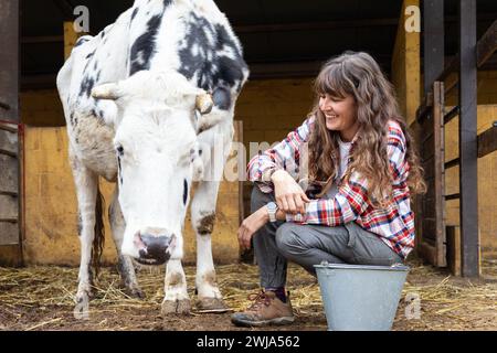 Ritratto di una giovane contadina sorridente con una mucca da latte. Benessere e cura degli animali in un'azienda agricola biologica. Foto Stock