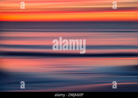 Movimento astratto sfocato di un tramonto vibrante con striature di rosso e blu sul Mar Mediterraneo Foto Stock