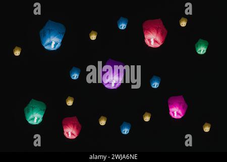 Le vivaci lanterne di carta sorgono nel cielo notturno, simboleggiando speranze e sogni durante una festa. Foto Stock
