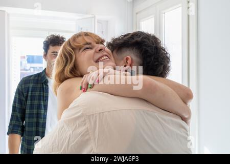 Primo piano di uomo e donna in abiti casual che si abbracciano vicino a raccolto un uomo adulto sorridente in un appartamento leggero Foto Stock