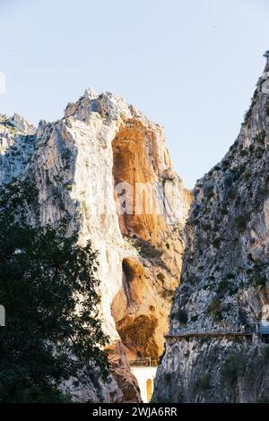 Vetta soleggiata di una massiccia formazione rocciosa con il sentiero Caminito del Rey lungo il lato di Malaga Foto Stock