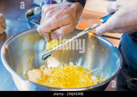 Mano di un uomo irriconoscibile con grattugia mentre preparano gustosi pancake di patate al ristorante Zermatt Svizzera Foto Stock