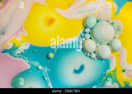 Un vivace abstract di colori gialli, blu e rosa con bolle bianche che creano un effetto marmorizzato sott'acqua Foto Stock