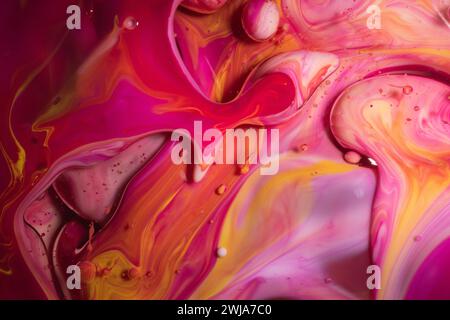 Un mix dinamico di fantasie di inchiostro rosa e giallo con bolle che creano un design astratto energico e vivace Foto Stock