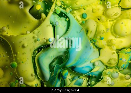 Una rinfrescante miscela di inchiostro verde lime e turchese si snoda con bolle effervescenti che creano un motivo astratto vivace e organico Foto Stock