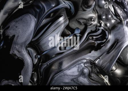 Astratto monocromatico di inchiostri girevoli neri e grigi con sottili bolle, creando una trama metallica misteriosa e fluida Foto Stock